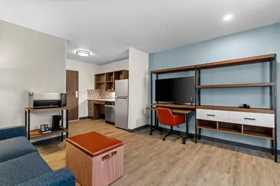 a living room with a couch and a desk with a tv at Everhome Suites Temecula in Temecula