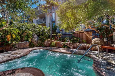 a hot tub in a yard with trees and a building at Breakwater Escape A 200 in Oceanside