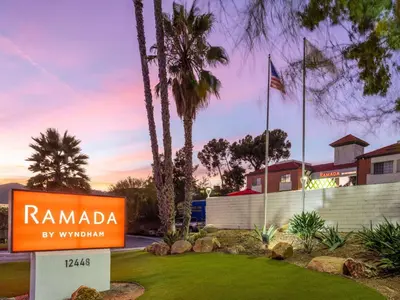 a sign for ramada by wynyard with palm trees at Ramada by Wyndham San Diego Poway Miramar in Poway