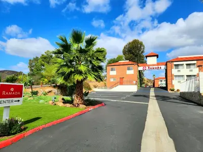 an empty street in front of a building with a palm tree at Ramada by Wyndham San Diego Poway Miramar in Poway