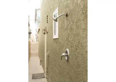 a stone wall with a shower on the side of a building at Lower West Newport in Newport Beach