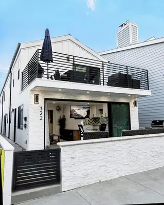 a white house with a balcony and an umbrella at Upper West Newport in Newport Beach