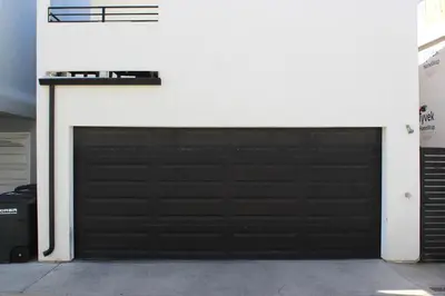 a black garage door on a white wall at Upper West Newport in Newport Beach