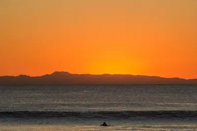 a person riding a wave in the ocean at sunset at 3 Bedrooms in Newport Beach