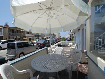 a table and chairs under an umbrella on a porch at Lower West Newport in Newport Beach