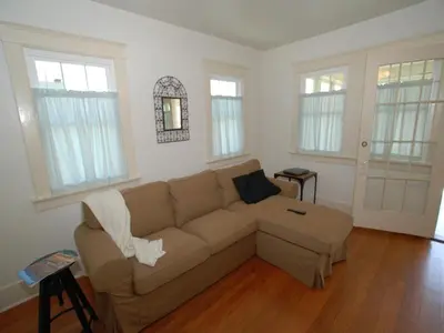 a living room with a brown couch and windows at Lower West Newport in Newport Beach