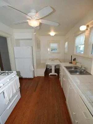 a kitchen with white cabinets and a ceiling fan at Lower West Newport in Newport Beach