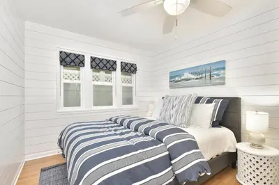 a white bedroom with a bed and two windows at 129 G St in Newport Beach