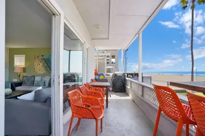 a balcony with orange chairs and a couch and the beach at 2010 W Oceanfront in Newport Beach