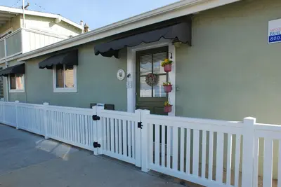 a house with a porch with a white fence at Lower West Newport in Newport Beach