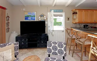 a kitchen with a television and a counter with chairs at Lower West Newport in Newport Beach