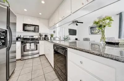 a kitchen with white cabinets and stainless steel appliances at 3 Bedrooms in Newport Beach