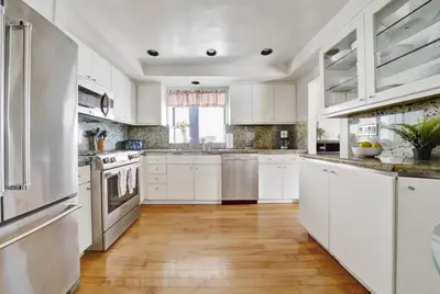 a white kitchen with white cabinets and a hardwood floor at 4 Bedrooms in Newport Beach