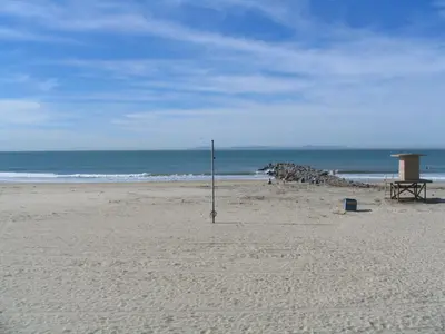 a beach with a bench and a pole in the sand at 3112 W Oceanfront A in Newport Beach
