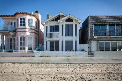 a house on the beach next to two buildings at 3112 W Oceanfront B in Newport Beach