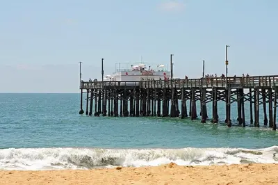 a pier with a boat sitting on top of the ocean at 3112 W Oceanfront B in Newport Beach