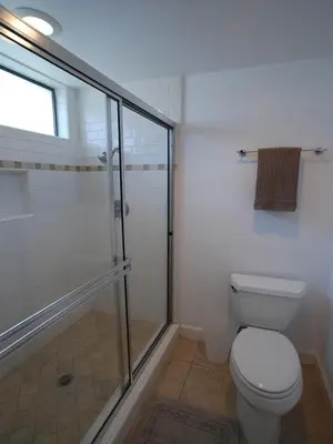 a bathroom with a toilet and a glass shower at 3112 W Oceanfront B in Newport Beach