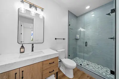 a bathroom with a toilet and a glass shower at Rooftop Home With Ocean View & Private Parking in Oceanside