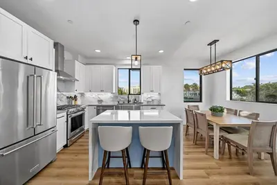 a kitchen with white cabinets and a table with chairs at Rooftop Home With Ocean View & Private Parking in Oceanside