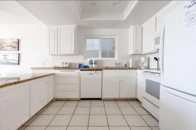 a white kitchen with white cabinets and white appliances at Beatrice - Beachfront in Newport Beach