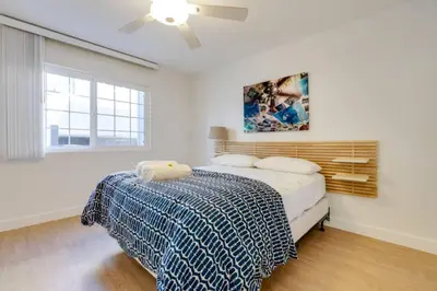 a white bedroom with a bed and a ceiling fan at Beatrice - Beachfront in Newport Beach