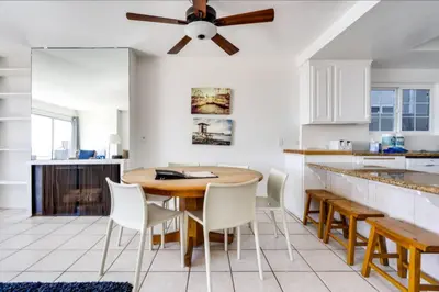 a kitchen with a table and chairs and a ceiling fan at Beatrice - Beachfront in Newport Beach