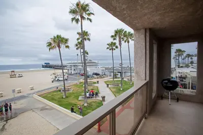 a view of the beach from a balcony with palm trees at Christina - Beachfront in Newport Beach