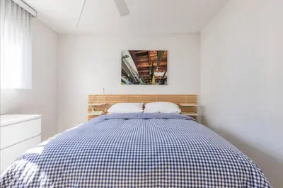 a bed in a white room with a checkered blanket at Alexander - Oceanview in Newport Beach