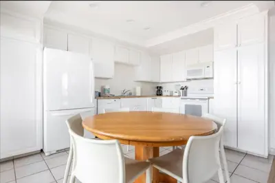 a kitchen with a wooden table and white cabinets at Benjamin - Oceanview in Newport Beach