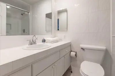 a white bathroom with a toilet and a sink at Benjamin - Oceanview in Newport Beach