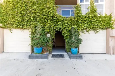 a building with two white garage doors with plants at Benjamin - Oceanview in Newport Beach