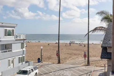 a beach with a white car parked on the sand at Christopher - Oceanview in Newport Beach