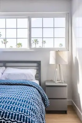 a bedroom with a bed with a blue blanket and two windows at Christopher - Oceanview in Newport Beach