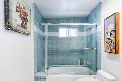a bathroom with a shower and a bathtub with blue tiles at Beachfront Home in Newport Beach
