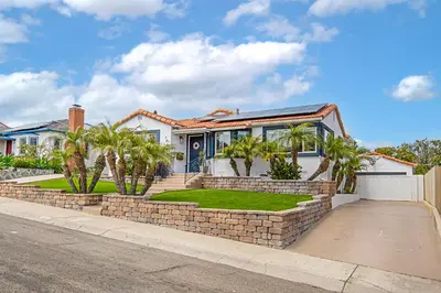 a house with a brick wall and palm trees at The Gathering Place - Guest Favorite with Huge Yard in San Diego