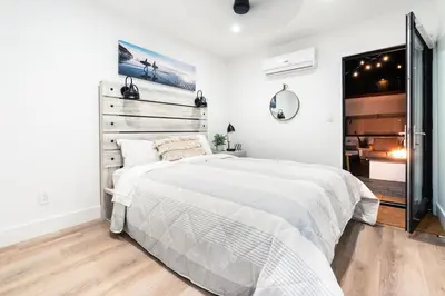 a white bedroom with a large bed and a bathroom at Private Beachside Home with HotTub in Carlsbad