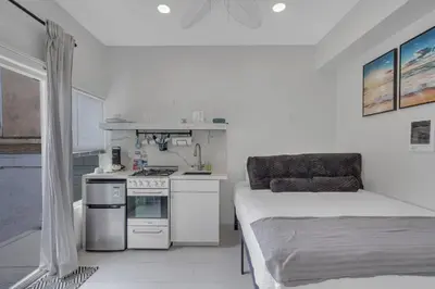 a small white kitchen with a bed and a stove at The Shining Sea Crab in Oceanside