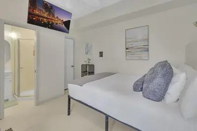 a white bedroom with a bed and a tv on the wall at The Shining Sea Octopus in Oceanside