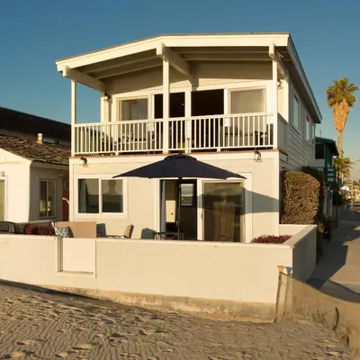 a white house with an umbrella in front of it at 3600 W Oceanfront in Newport Beach