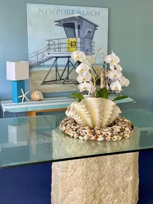 a glass table with a vase with white flowers on it at 4210 Seashore Dr in Newport Beach