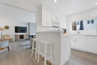 a kitchen with white cabinets and a kitchen island with stools at 5408 Seashore Dr A in Newport Beach