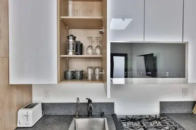 a kitchen with white cabinets and a sink at Bungalow near zoo and beach with AC, EV, private yard in San Diego