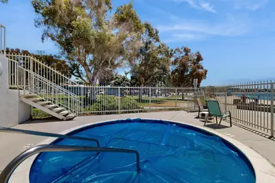 a blue swimming pool with chairs and a fence at Tranquil Escape Bayside in San Diego