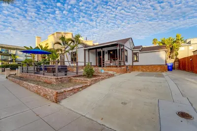 a house with a patio with a blue umbrella at Sail Bay Dream - Steps to the bay! in San Diego