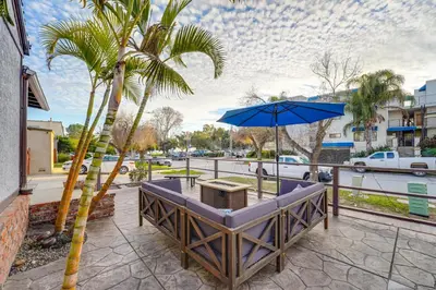 a table with a blue umbrella and a palm tree at Sail Bay Dream - Steps to the bay! in San Diego