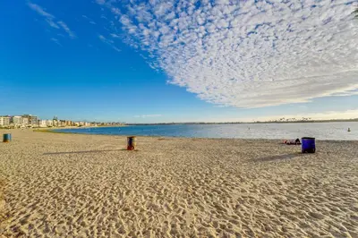 a beach with two trash cans in the sand at Sail Bay Dream - Steps to the bay! in San Diego