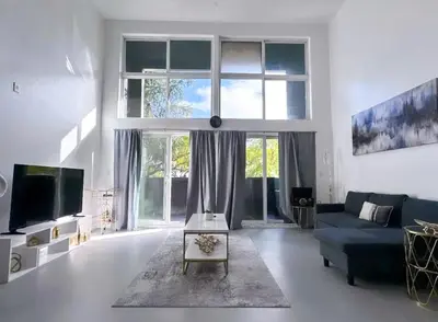 a living room with a blue couch and a large window at Beautiful Loft in Little Italy SD with Parking in San Diego