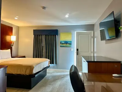 a hotel room with a bed and a desk at Oceanside Inn & Suites in Oceanside