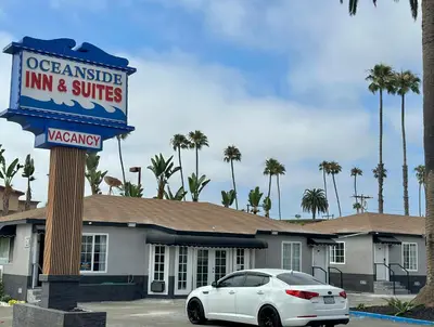 a white car parked in front of a inn and suites at Oceanside Inn & Suites in Oceanside
