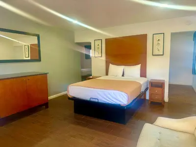 a hotel room with a bed and a mirror at Oceanside Inn & Suites in Oceanside